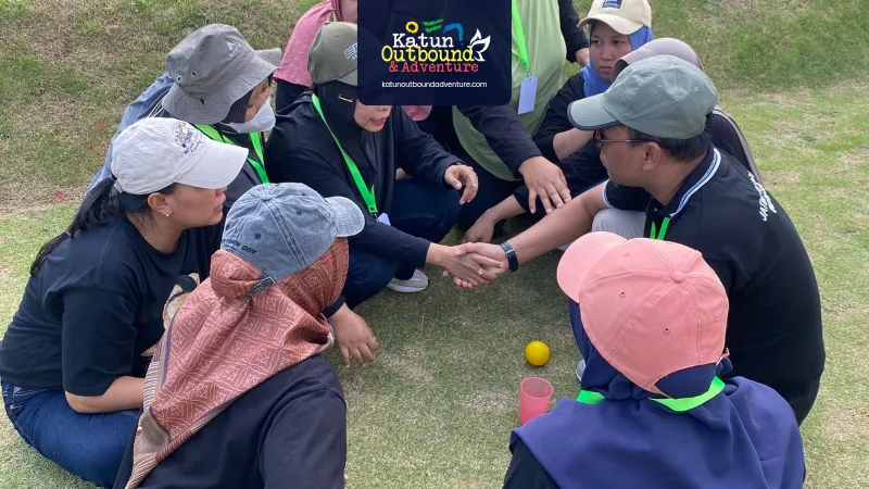 outbound Fasilitator memandu sesi debriefing peserta outbound duduk melingkar di rumput
