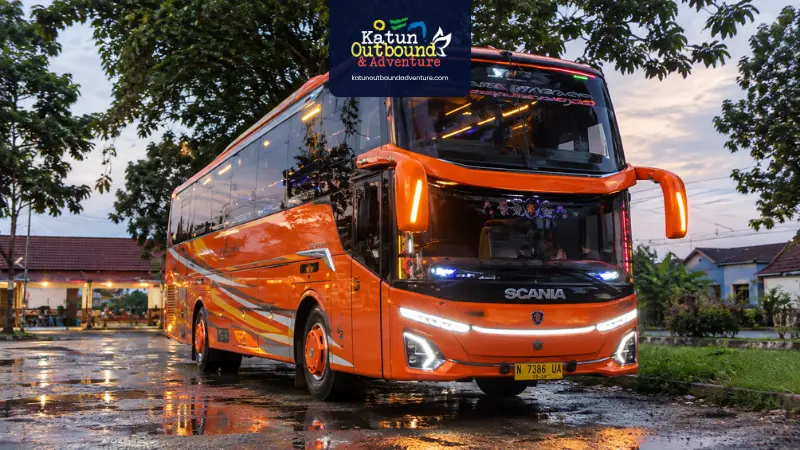 Bus pariwisata besar tiba di venue outbound dengan jalan aspal lebar